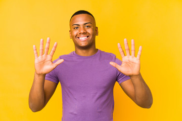 Young latin man isolated on yellow background showing number ten with hands.