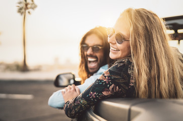 Happy young couple doing road trip in tropical city - Travel people having fun driving in trendy...
