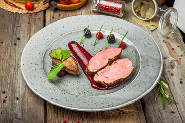 Medallions of veal, with sauce on a plate. Wooden background