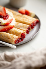 french crepe filled with caramel fudge and decorated with chocolate fudge, berries castor sugar and mint leaves on marble background with copy space