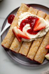 french crepe filled with caramel fudge and decorated with chocolate fudge, berries castor sugar and mint leaves on marble background with copy space