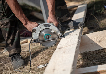 A worker saws a wooden beam.