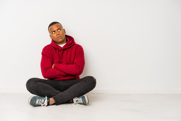 Young latin man sitting on the floor isolated tired of a repetitive task.