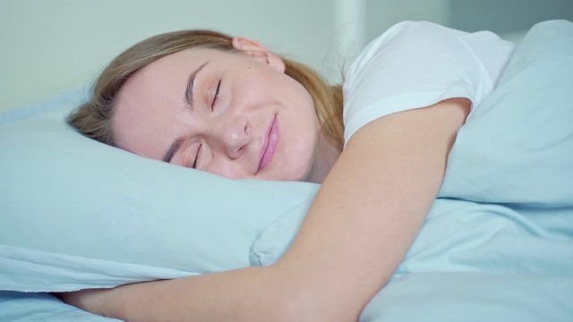 Woman sleeping well in bed hugging soft white pillow. Teenage girl resting, good night sleep concept