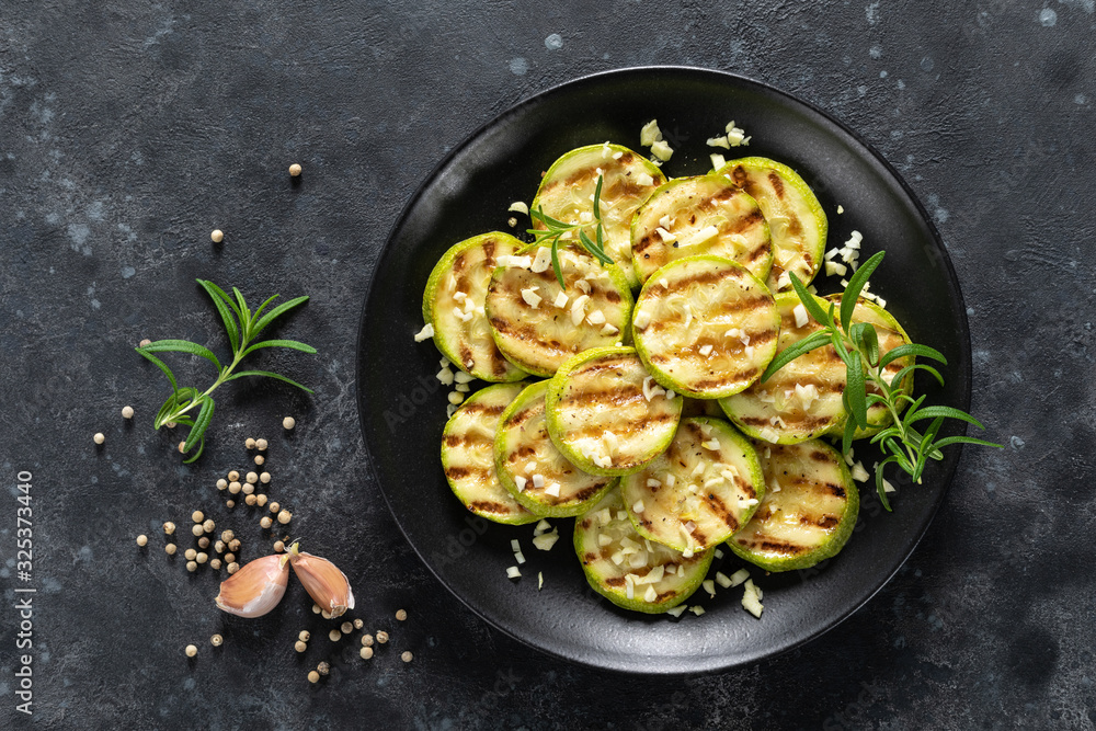 Sticker grilled zucchini, courgette with garlic and rosemary on plate, top view