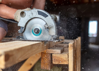 A worker saws a wooden beam.