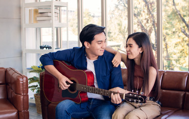 A man is playing guitar for his girlfriend