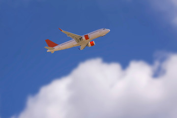 Fototapeta na wymiar An airline plane in the blue sky flying above big white blurred clouds. Image with copy space.