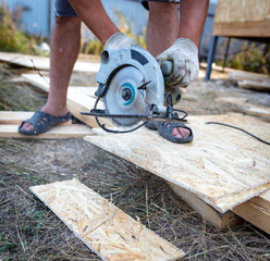 A worker saws a wooden beam.