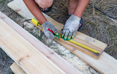 A worker measures a wooden workpiece with a meter.