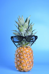 Pineapple in sunglasses close-up on blue background