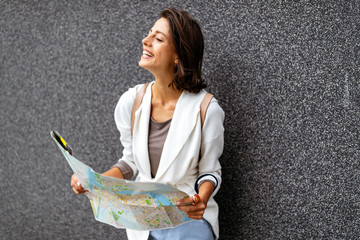 Happy young woman traveler with backpack and map on the street.