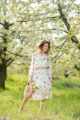 A gorgeous girl walks in a flowering spring garden. The concept of unity of man with nature