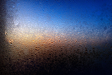 Drops of water on a glass in blue in the morning.