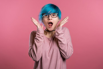 Pretty female shocked model with colorful hairstyle on pink background. OMG, wow effect. Girl with delight. Surprised excited happy woman