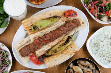 Traditional Turkish Adana kebab or kebap meat food, appetizers, ayran and salgam on table from top view in turkish restaurant.