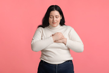 Grateful plus size girl keeping both palms on chest, expressing appreciation