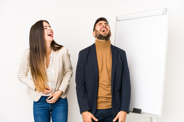 Young caucasian business couple isolated laughs happily and has fun keeping hands on stomach.