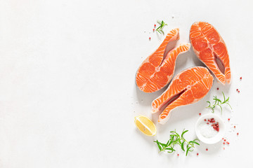 Salmon. Fresh raw salmon fish steaks with cooking ingredients, herbs and lemon on white background, top view