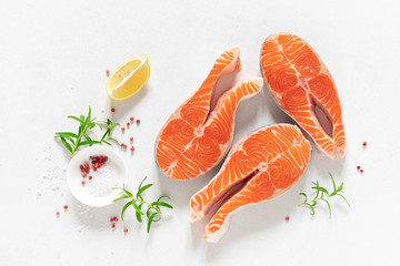 Salmon. Fresh raw salmon fish steaks with cooking ingredients, herbs and lemon on white background,...