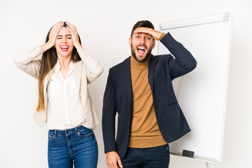 Obraz premium Young caucasian business couple isolated laughs joyfully keeping hands on head. Happiness concept.