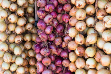 Closeup of strings of yellow and red onions in roadside food market, Cuba