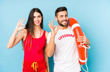 Young lifeguard couple isolated cheerful and confident showing ok gesture.