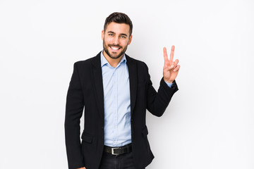 Young caucasian business man against a white background isolated showing victory sign and smiling broadly.