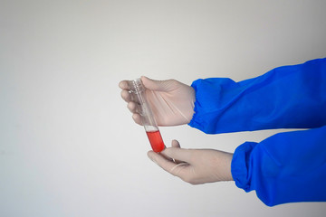 Hands in a protective biological suit holding a test tube. On white background. Discovery of a coronavirus vaccine