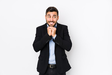 Young caucasian business man against a white background isolated keeps hands under chin, is looking happily aside.