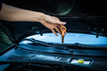 Caucasian white male dirty carpenter hand holding greasy plastic dipstick checking synthetic motor oil level for car engine maintenance