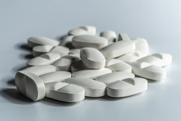 Closeup of many prescription drugs, medicine tablets or vitamin pills in a pile on white background...