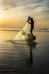 Fototapeta na wymiar Silhouette of traditional fishermen throwing net fishing at sunrise time, livelihoods of fishermen at Pakpra, Phatthalung in Thailand