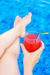 Woman with cocktail sitting near the swimming pool.