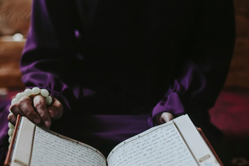 Praying young muslim woman. Middle eastern girl praying and reading the holy Quran. Muslim woman studying The Quran at home