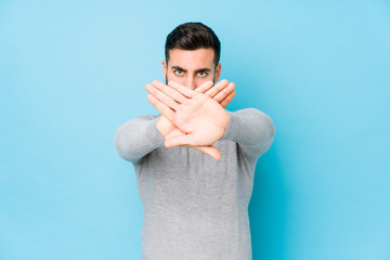 Young caucasian man against a blue background isolated doing a denial gesture