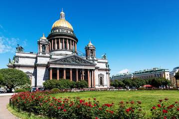 The view from the side of the square with bushes of red roses on St. Isaac's cathedral on a sunny summer day. Saint Petersburg, Russia.