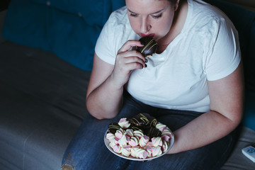 Emotional eating, mental disorder, depression, loneliness, stress. Lonely woman eating sweets and...