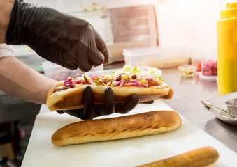 The chef cooking hot dog on a grill. Restaurant.
