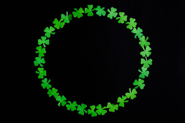 St Patricks Day Flat Lay including shamrocks in the form of a circle on black background.