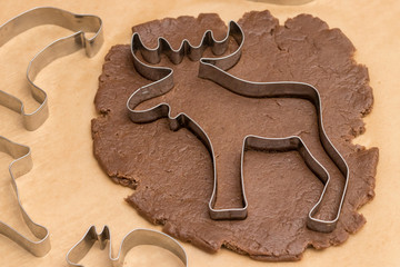 A moose-shaped cookie mold lies on a small rolled piece of brown dough