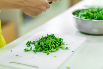 Cook in the kitchen cuts greens close up