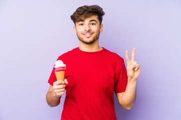 Young arabian man holding a ice cream showing number two with fingers.