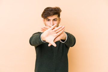 Young arabian man isolated on a beige background doing a denial gesture