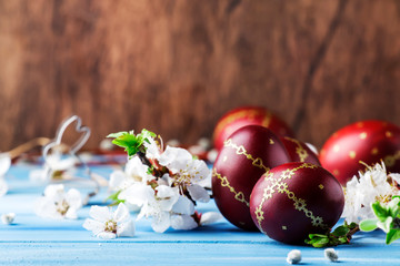 Red Easter eggs. white flowers and willow branches on gentle Easter blue wood background