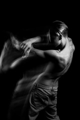Obraz na płótnie Canvas Naked back curves. Beautiful fuzzy mystical mysterious ambiguous original conceptual profile side portrait of young blonde man on a black background. Black and white photo series. long exposure