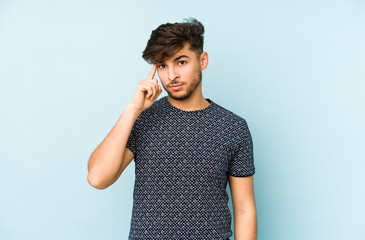 Young arabian man isolated on a blue background pointing temple with finger, thinking, focused on a task.