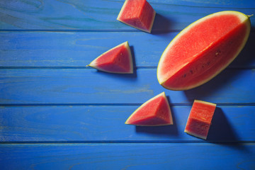Sliced watermelon on a wooden table with a blue background. Summer concept