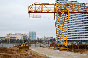 A large modern construction site in the construction of buildings and houses with appliances and many large high tower and stationary industrial powerful cranes and building materials