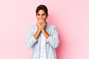 Young caucasian man posing in a pink background isolated laughing about something, covering mouth with hands.